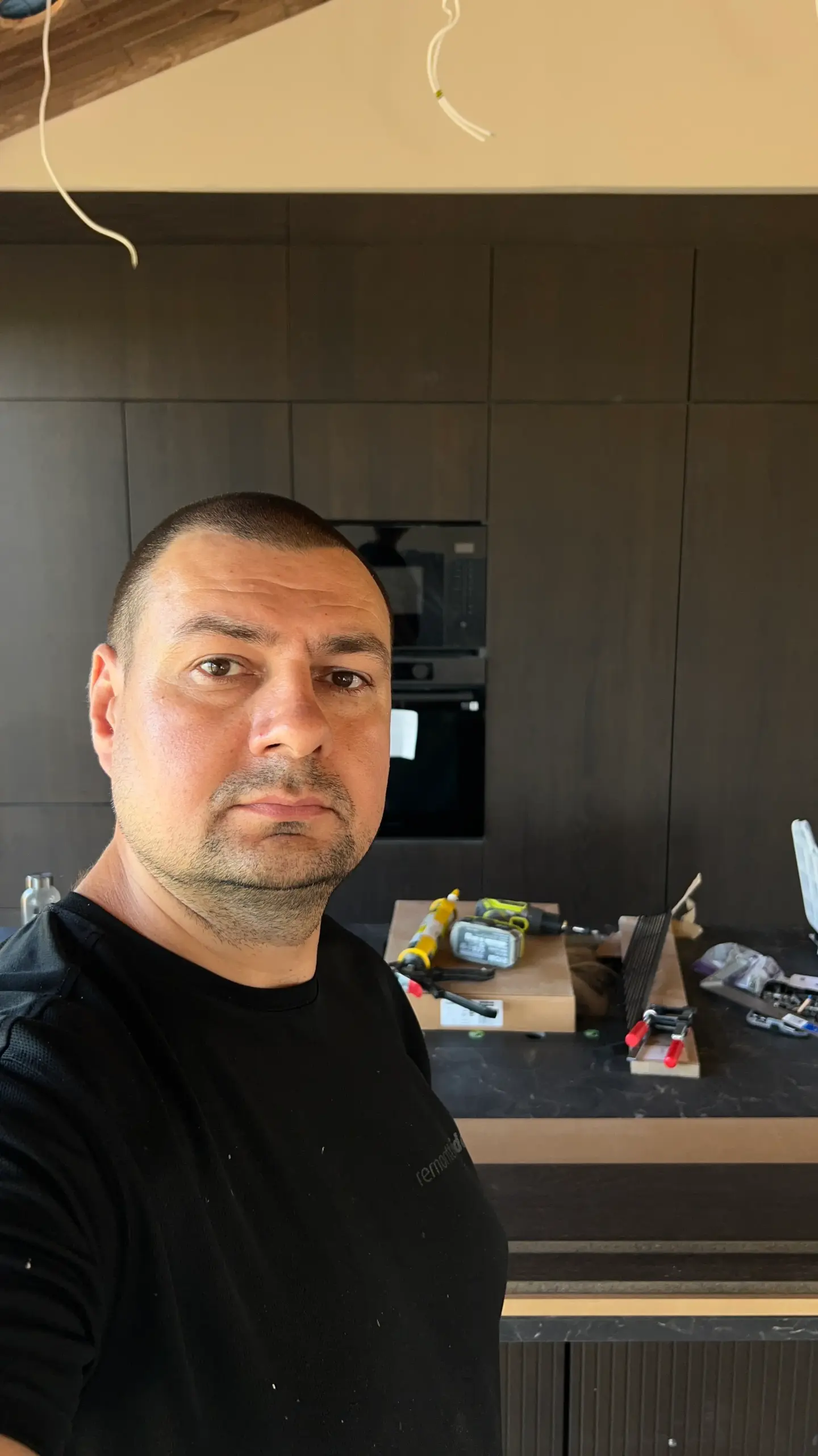 Kalusteasentaja valmiin keittiön edessä Oulussa